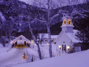 雪村，黃昏時教堂和橋樑被節日燈光照亮。 — 冬季風景 壁紙