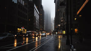 黃昏時分雨中的城市街道，濕漉漉的路面和霧中的摩天大樓。 — 暗黑美學電腦 壁紙
