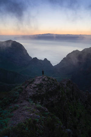 黎明時分站在山頂眺望大海和雲層的人 — 孤獨 壁紙