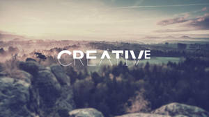 黎明時分霧氣瀰漫的山景，帶有「CREATIVE」文字覆蓋。 — 黎明 壁紙