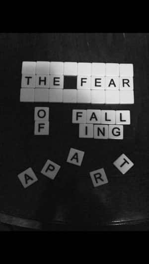 Scrabble 字母牌在深色表面上拼出「the fear of falling apart」。 — 教堂 壁紙
