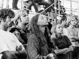黑白照片，人們從體育場看台交叉雙臂觀看。 — Woodstock 壁紙