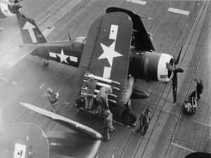 水手在航空母艦甲板上維修二戰戰鬥機。 — 戰爭機器 壁紙