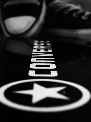 Converse 標誌投射在反光表面上，背景有模糊的運動鞋。 — 3:4 壁紙