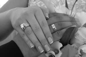 兩隻手緊握在一起，戴著結婚戒指，附近有白色花朵。 — 婚禮 壁紙
