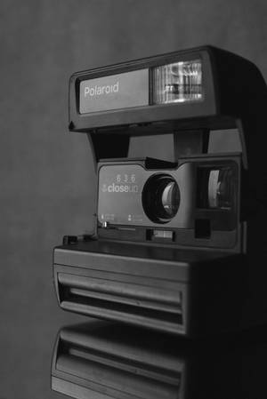 復古Polaroid 636近攝相機，閃光燈亮起，反射在深色表面上。 — 復古90年代風格 壁紙
