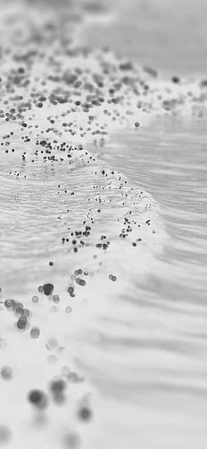 海浪與鵝卵石拍打沙灘，黑白畫面。 — iPhone 14 Plus 壁紙