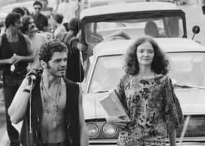 一男一女在繁忙的街景中走過復古汽車。 — Woodstock 壁紙