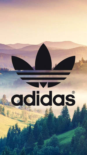 Adidas標誌疊加在日落時分有霧和樹木的山谷上。 — 愛迪達 GIF 壁紙
