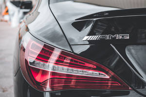 黑色AMG汽車後方，帶紅色尾燈和鍍鉻標誌。 — Mercedes-Benz 壁紙