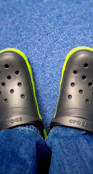 黑色Crocs配螢光黃飾邊，藍色地毯上。 — Crocs 壁紙