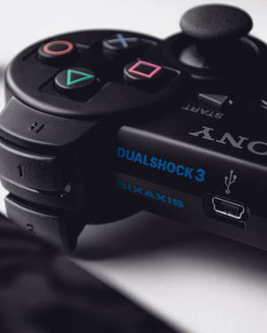 黑色PlayStation 3手把的特寫，帶有彩色按鈕和藍色文字。 — PS3 壁紙