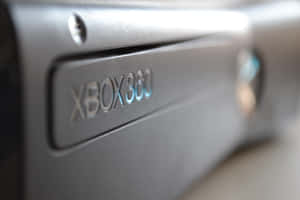 黑色Xbox 360遊戲主機特寫，帶有發光藍色標誌。 — MacBook Pro 14 壁紙