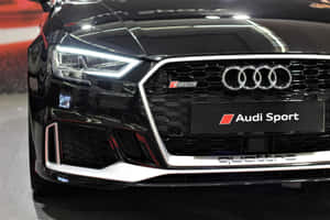 黑色Audi RS3前格柵、亮起頭燈及Audi Sport徽章的近距離特寫。 — Surface Laptop 壁紙