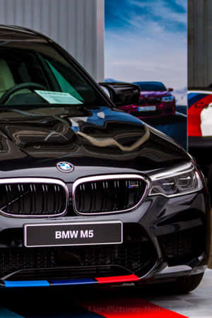 黑色BMW M5跑車帶有M Performance條紋，室內展示。 — Huawei MatePad Air (2025) 壁紙