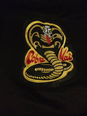 黑色布料上帶有 'Cobra Vai' 文字的刺繡眼鏡蛇補丁。 — 眼鏡蛇道館 壁紙