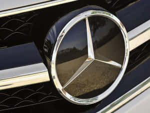 黑色汽車格柵上鍍鉻賓士標誌，反射樹木和天空。 — Mercedes-Benz 壁紙