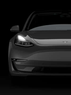 黑暗中灰色Tesla汽車前部的特寫，車頭燈亮起。 — iPad 第9代 壁紙