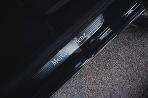 黑色賓士門檻，碎石表面上有鍍鉻標誌。 — Mercedes Benz C300 壁紙